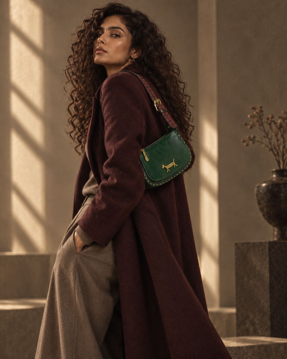 Rear three-quarter view of the same model, the green bag carried over her shoulder in raking daylight.