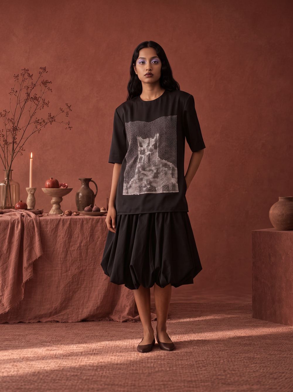 Black printed tee over a black bubble skirt in a terracotta room.