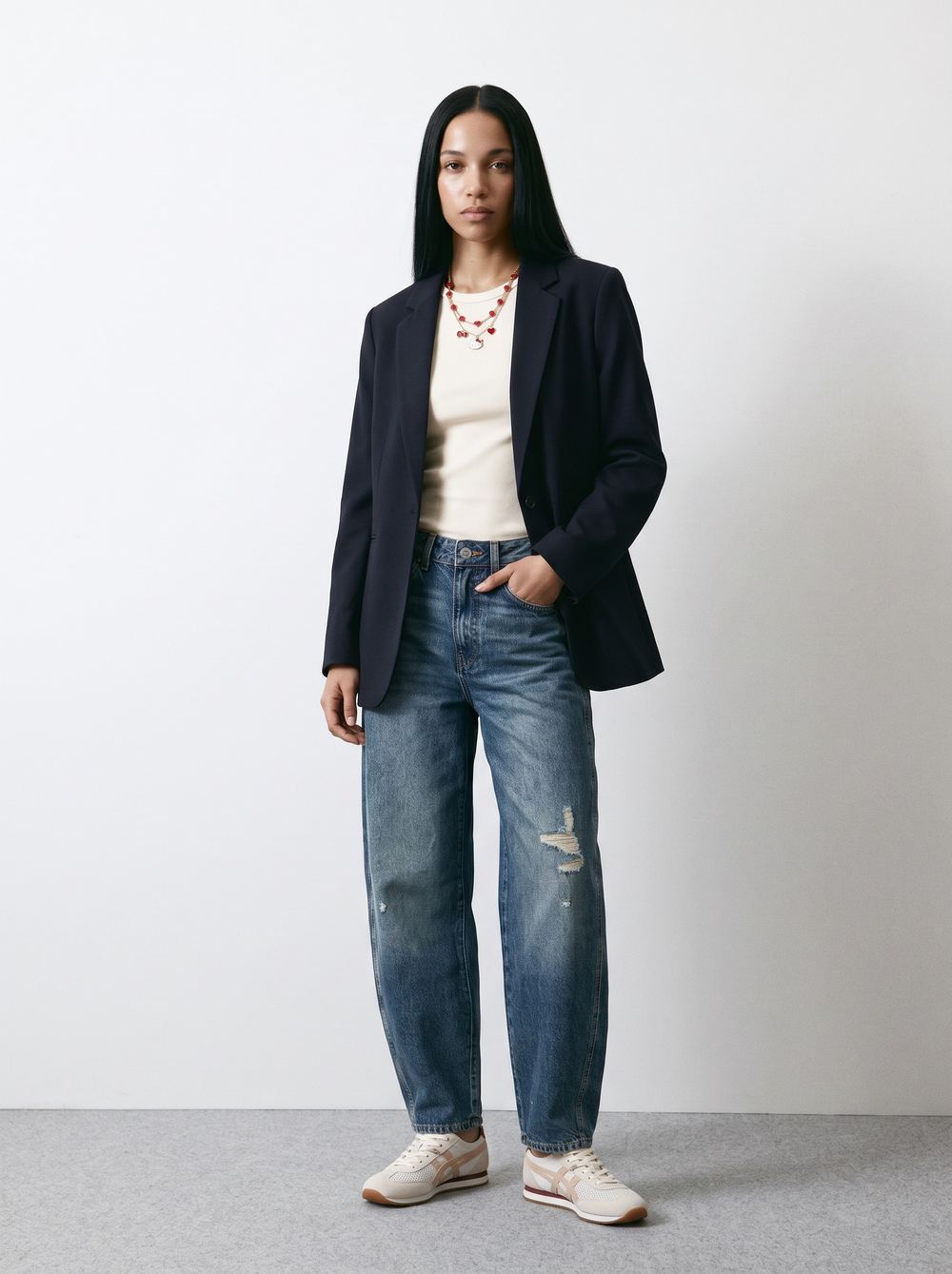 Full-length studio frame of a navy blazer over a white tee with blue jeans and white sneakers.