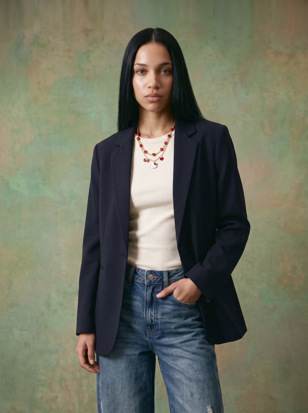 Navy blazer and jeans against a mottled green painted backdrop.