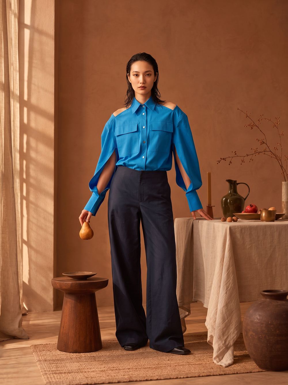 Blue shirt with slit sleeves over navy wide-leg trousers in a warm room.