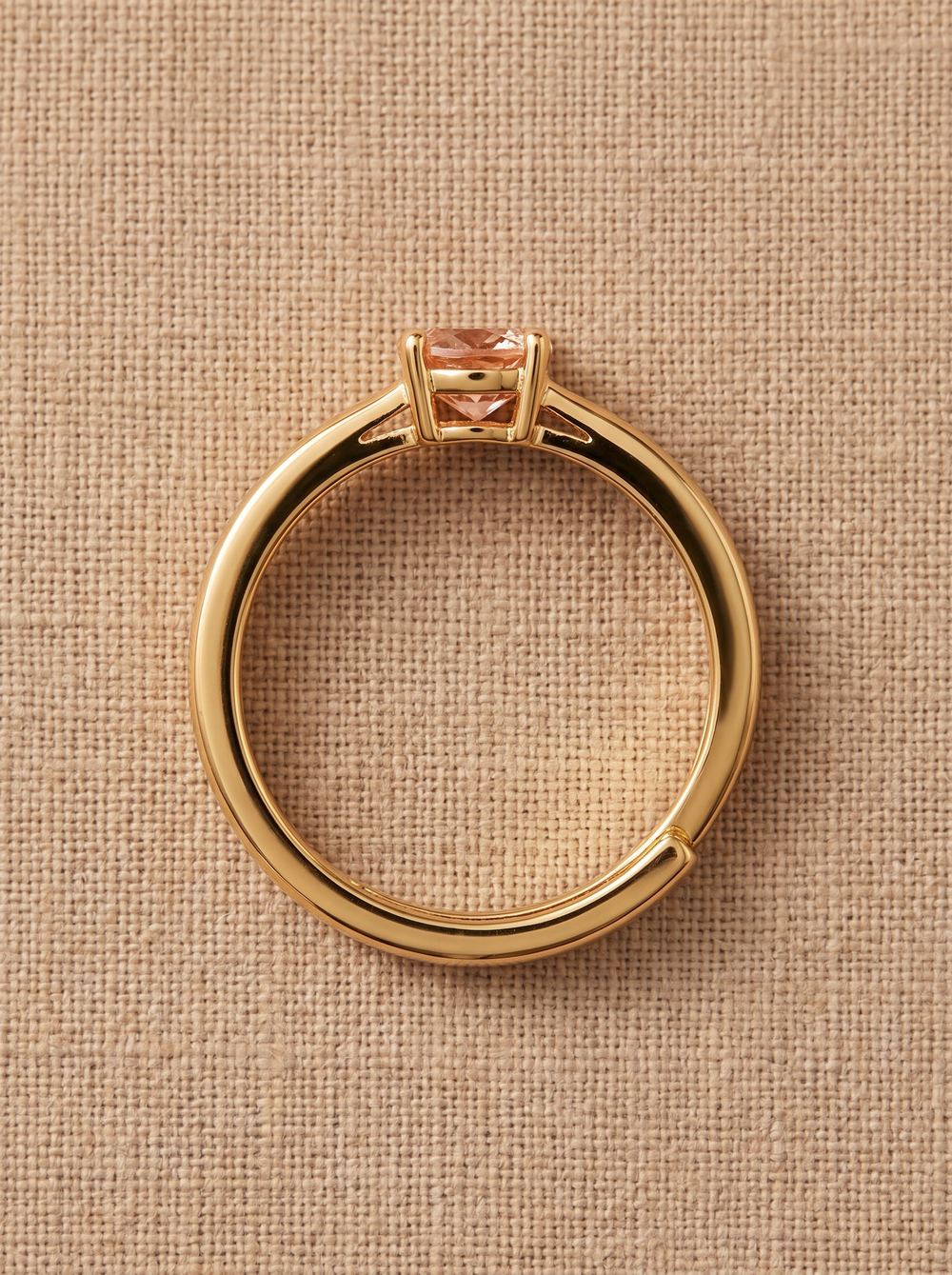 Gold ring standing on linen, the stone catching the light.