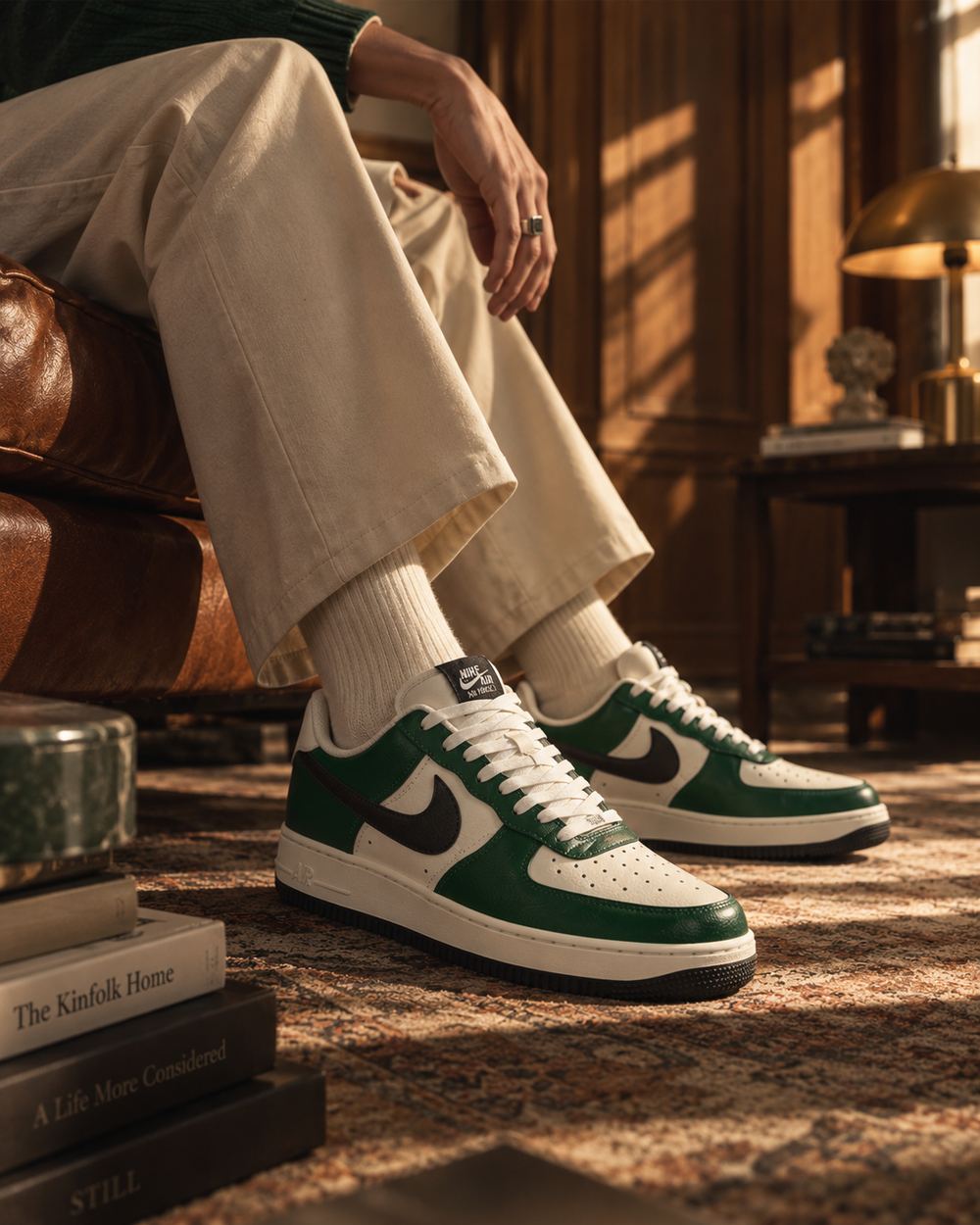 Low view of green and cream leather sneakers on a seated figure, warm lamplight and a patterned rug in a wood-panelled room.