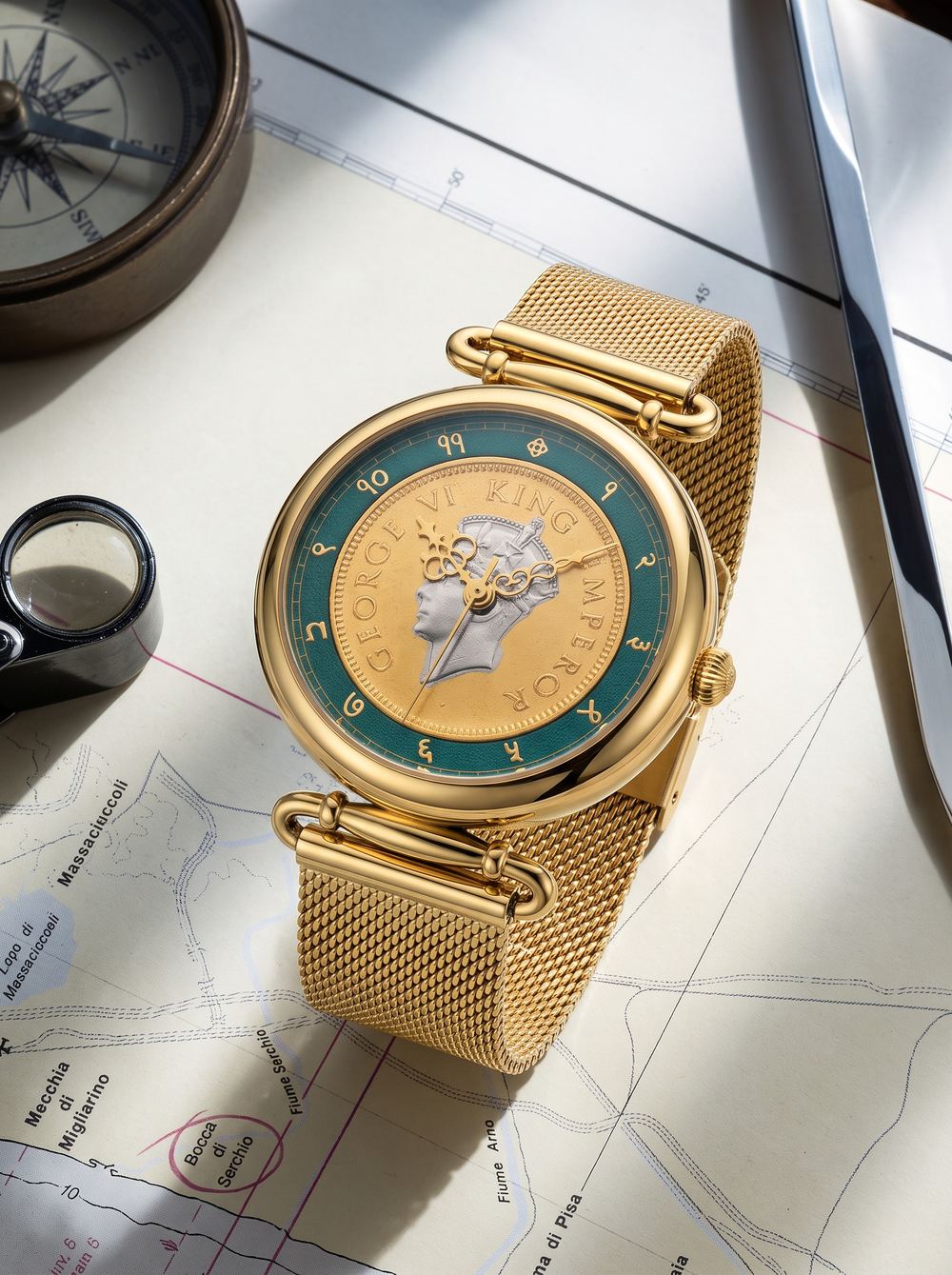 Gold mesh-strap coin watch lying on a vintage map beside a compass.